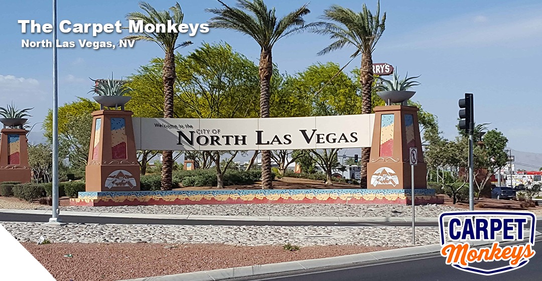 Welcome sign for North Las Vegas, featuring palm trees and desert landscaping, with The Carpet Monkeys logo and contact information for local cleaning services.