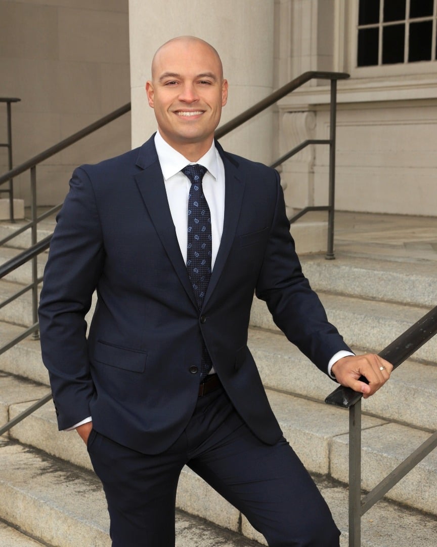Ricardo Torres, owner of The Carpet Monkeys, standing confidently on steps in a suit, representing professionalism and commitment to quality cleaning services in Las Vegas, NV.